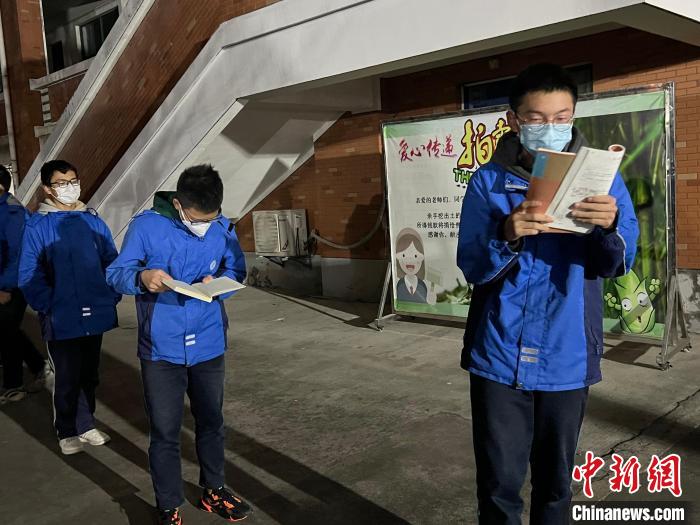 学生边排队等待核酸检测,边看书。 陈玮 摄