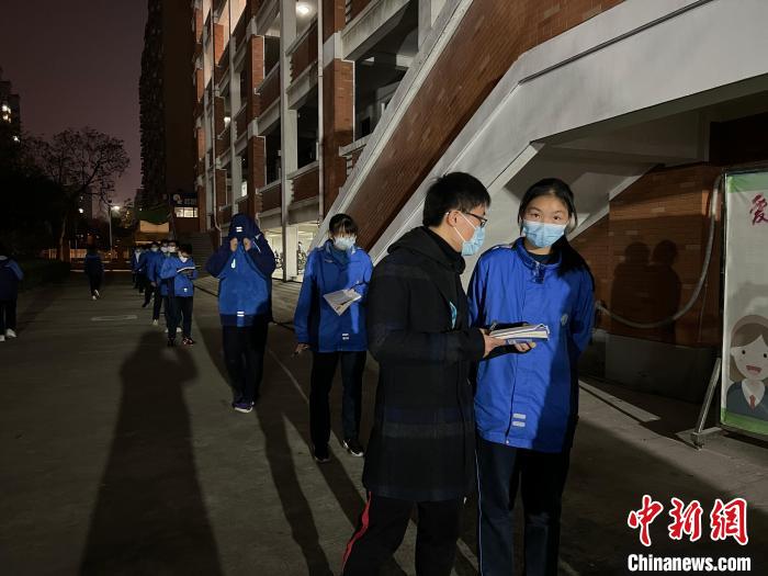 教师给排队等核酸检测的学生讲题。 陈玮 摄