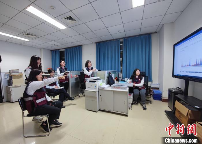 图为杨改英(左一)和部门同事正在进行疫情信息分析。 阚力 摄