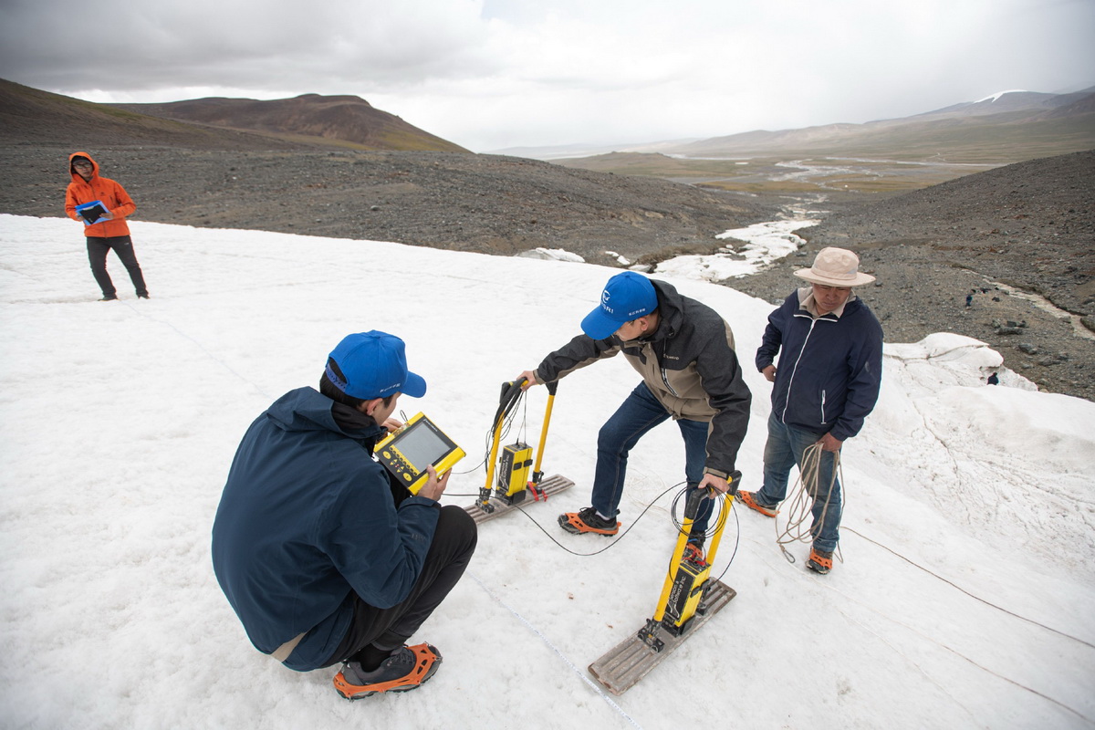 7月28日，在格拉丹东雪山，来自长江科学院的科考队员定培中（左一）、董士琦（左二）、范越（左三）在使用地质雷达探测冰川。