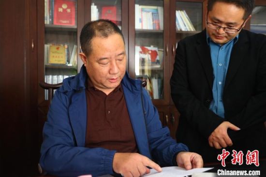 图为进顺村党委书记、村委会主任罗来昌(左)与同事交谈工作。　记者 刘占昆 摄