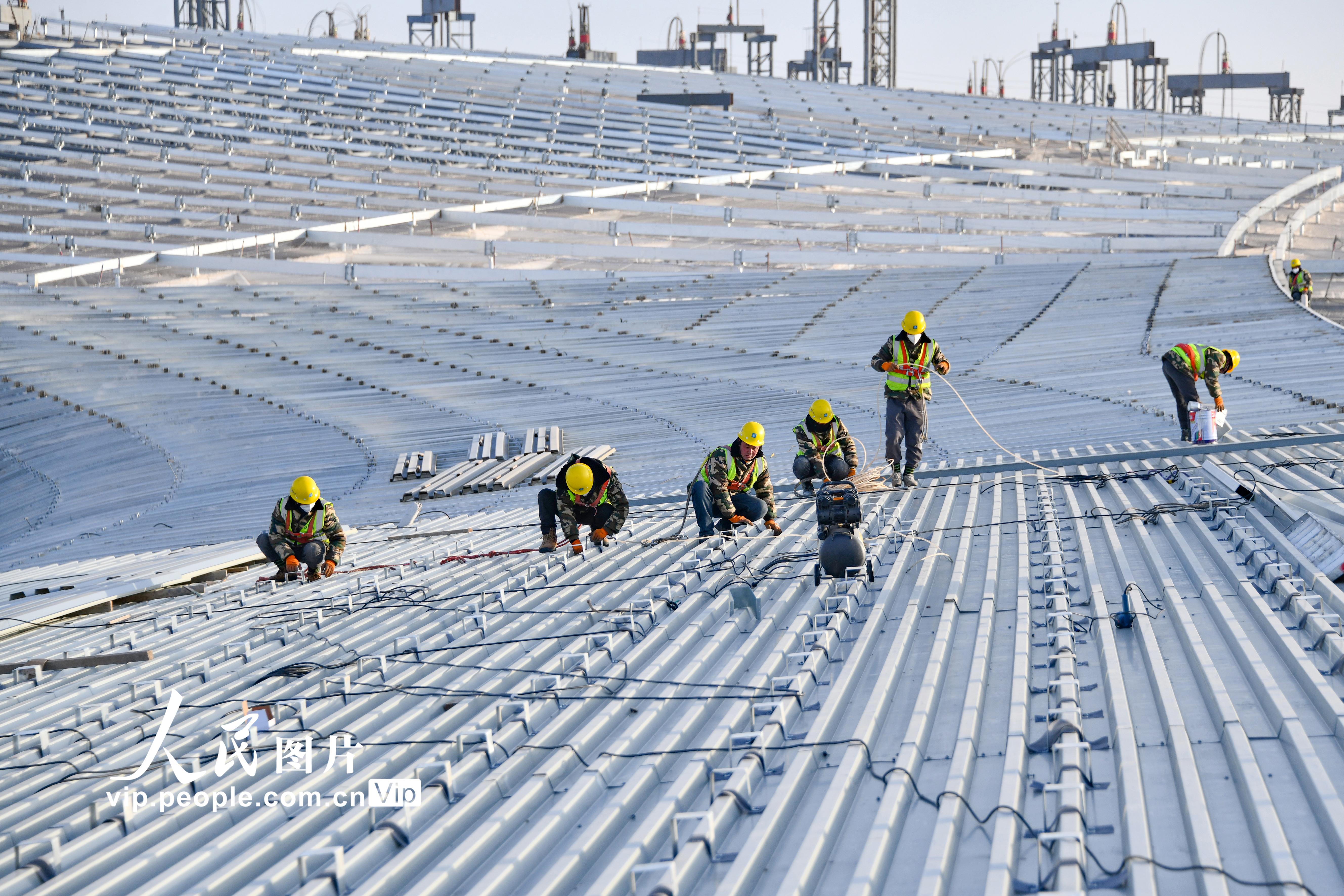 12月20日，甘肃兰州中川国际机场三期扩建工程工人正冒着严寒抢工期，在航站楼顶部进行金属屋面施工。