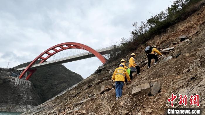 图为女子特检组成员攀爬陡坡，到郑渝高铁巫山大宁河大桥上方进行勘察。　肖江川 摄