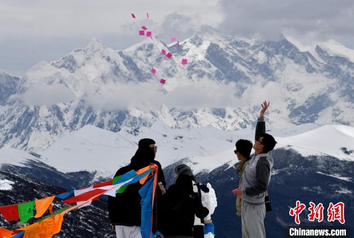 图为5月14日，游客在西藏林芝色季拉山观景台抛洒“隆达”(风马旗，藏族民众的一种祈福方式)。　李林 摄